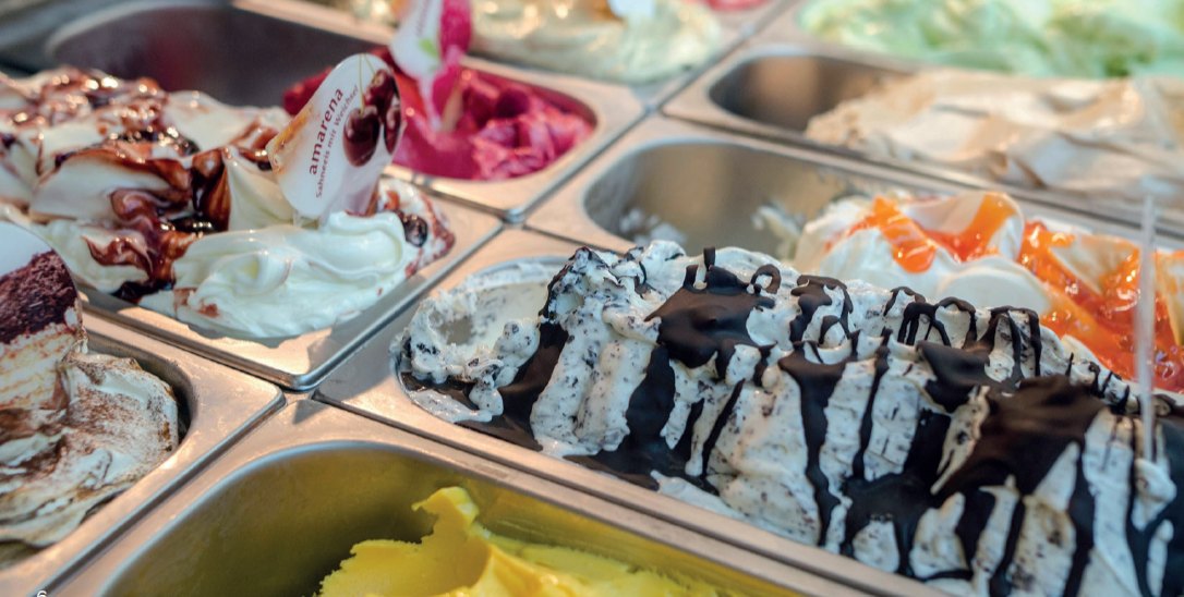 A gelato counter filled with trays of different flavours